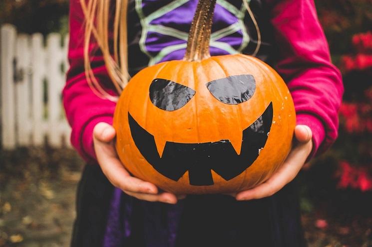 Un enfant déguisé tenant une citrouille pour Halloween