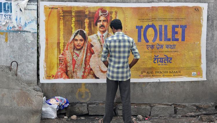 personne urinant devant l'affiche du film Toilet