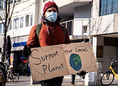 Une écologiste avec une pancarte support your local planet