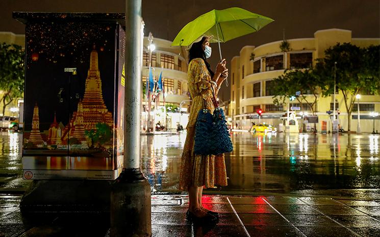 Une femme thailandaise sous la pluie dans les rues de Bangkok la nuit