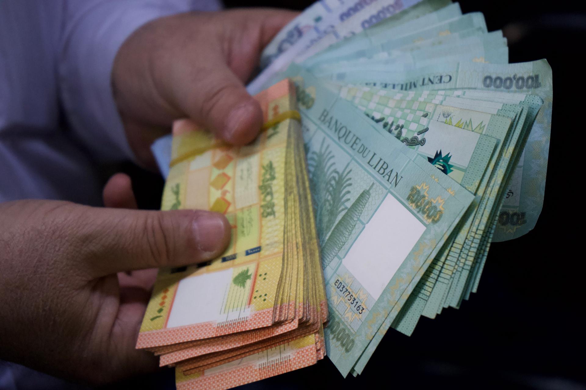 Dans un bureau de change, un homme tient différentes coupures de Livres libanaises. 