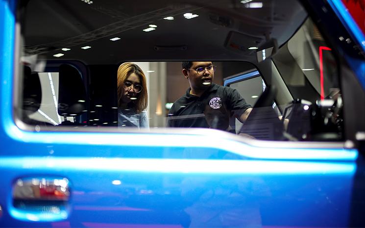 Des visiteurs regardent une voiture au salon de l'auto de Bangkok en juillet 2020