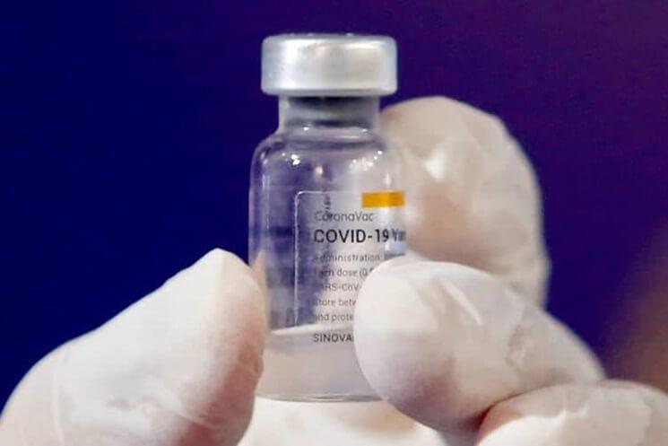 Fiolle de vaccin anti corrona tenue dans une main recouverte de gant en plastique