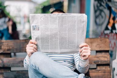 Une personne cachée derrière son journal