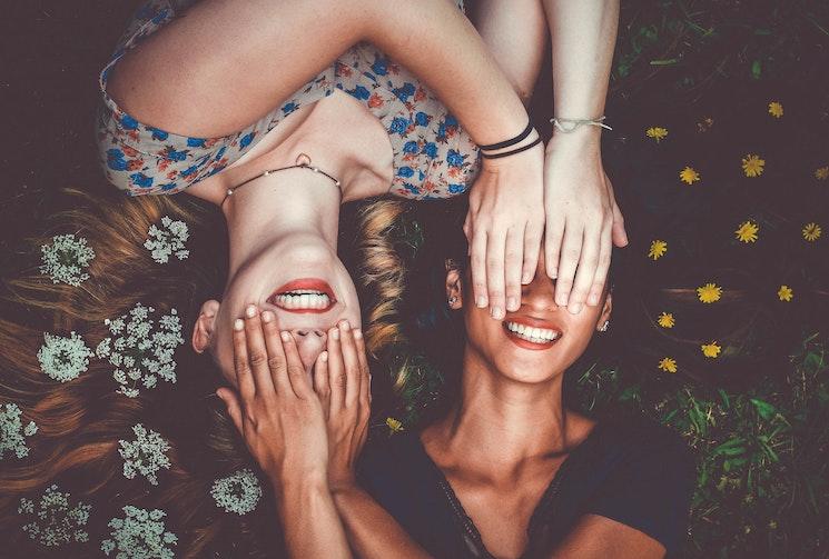 Deux jeunes femmes allongées dans l'herbe avec le sourire