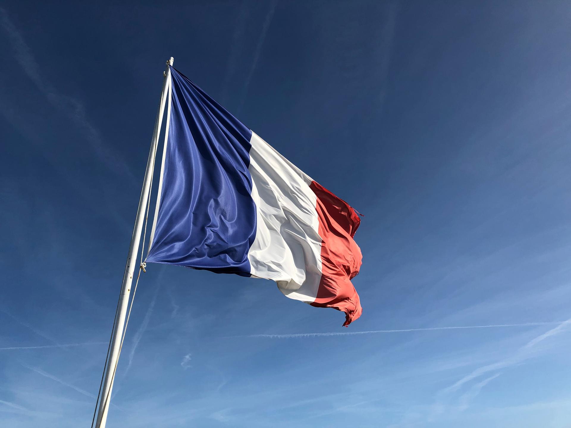 Un drapeau français avec un ciel clair en fond.