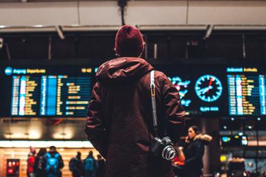 Un homme se tient devant les panneaux d'arrivées à l'aéroport 