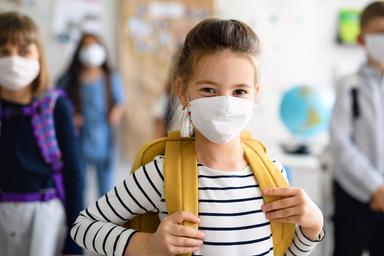 petite fille avec un sac à dos qui porte un masque