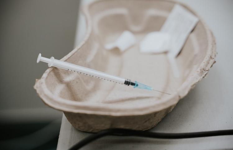 Une seringue de vaccin anti-covid posée dans une coupelle