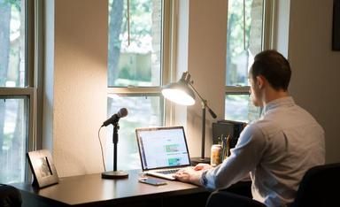 un homme en chemise blanche travaille avec son ordinateur portable en télétravail