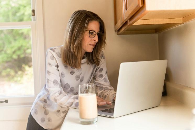 une femme consulte son ordinateur, dans son logement, en Espagne