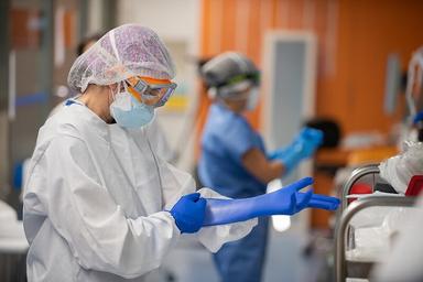 un chirurgien de l'hospital clinic, à Barcelone, enfile ses gants avant une opération