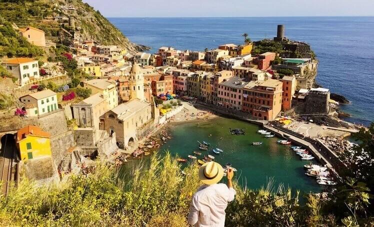 un homme en chapeau en vacances dans un village devant la mer en Italie