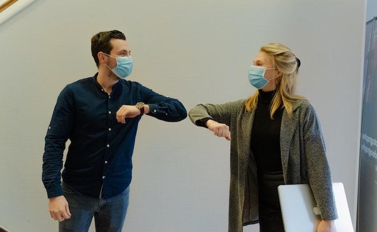 un homme et une femme avec des masques qui se touchent par le coude