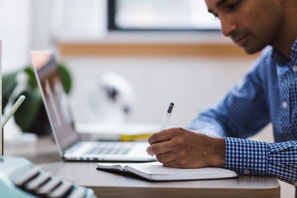 homme qui prend des notes devant ordinateur