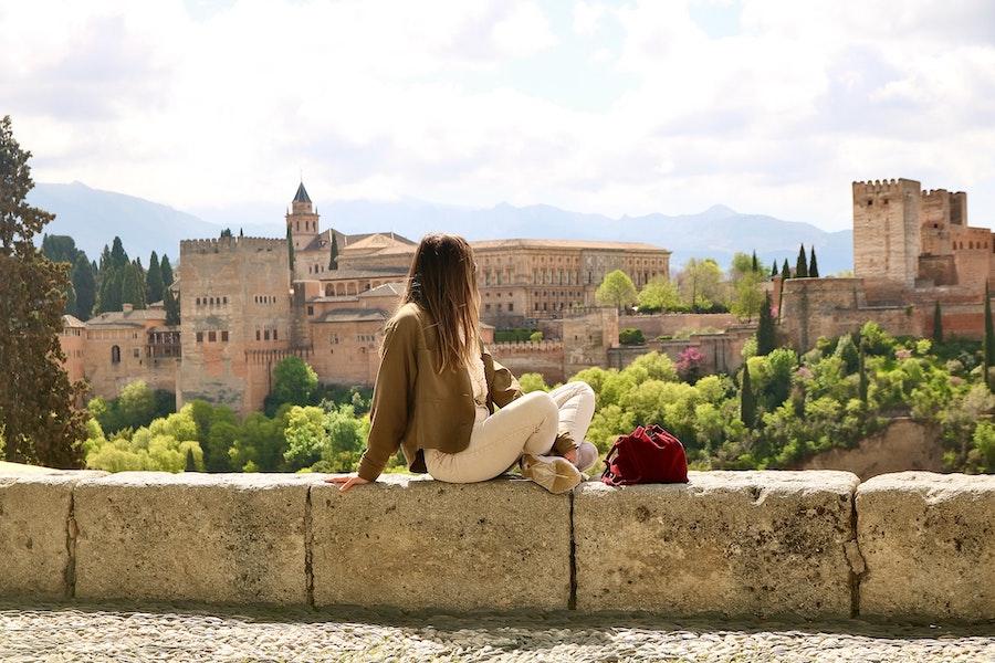 une femme sur un mur en train de regarder un bâtiment ancien