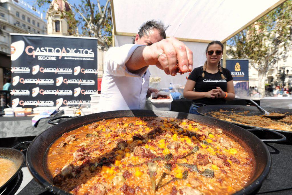 Une grande poêle de paella avec un cuisinier derrière 