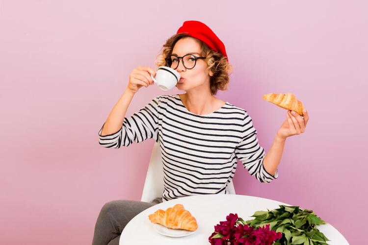 une femme avec un beret rouge en train de boire un cafe