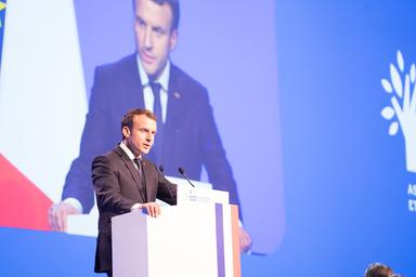 Le président Emmanuel Macron en train de parler sur un pupitre avec le drapeau français