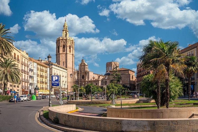 une place avec une eglise et un palmier sous le ciel bleu