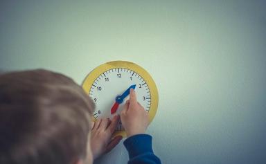 enfant tourne les aiguilles d'une horloge en papier