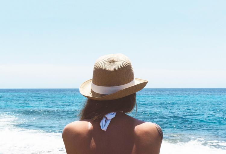 Une femme avec un chapeau face a la mer a Valence