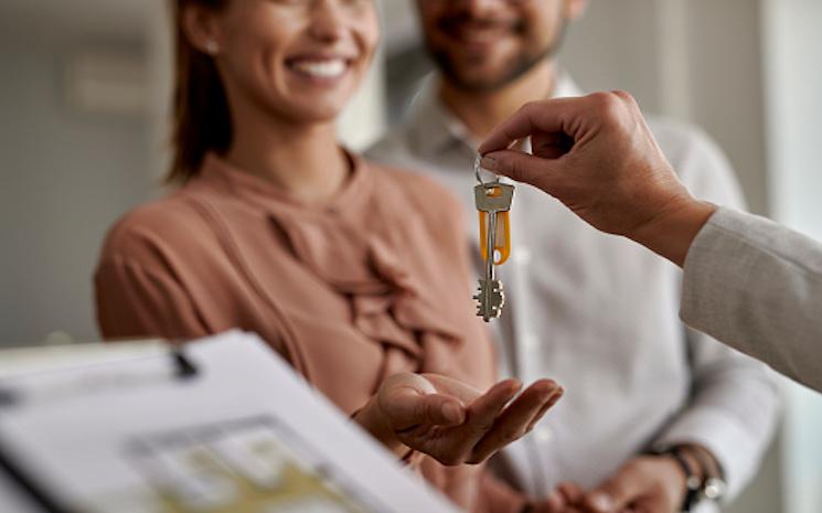 Personne qui tend les clés d'une maison à un couple 