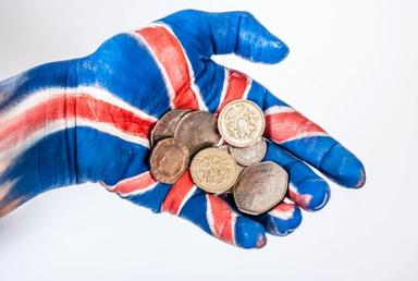 Une main peinte tient des pièces de monnaie britannique