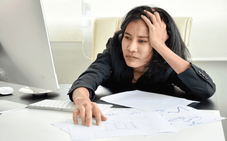 Une femme fatiguée de travailler devant un ordinateur et envisageant le quiet quitting