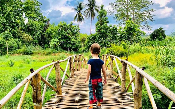 Un enfant sur un pont de bois face a la nature en Thailande