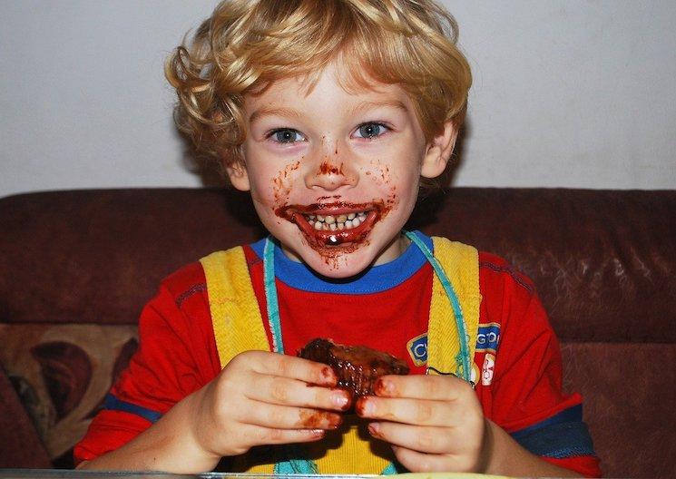 Petit garçon bouche pleine de chocolat