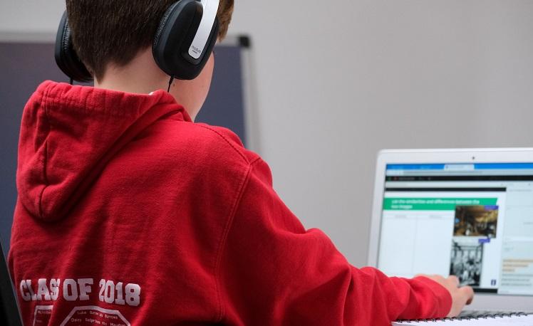 enfant avec un casque devant son ordinateur portable