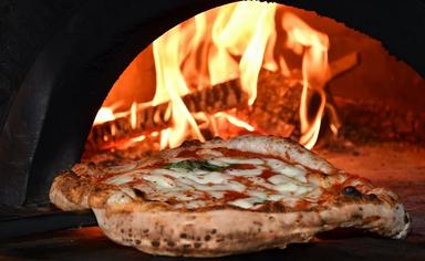 une pizza margherita qui sort du four à bois