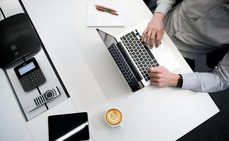 un homme écrit sur son ordinateur portable