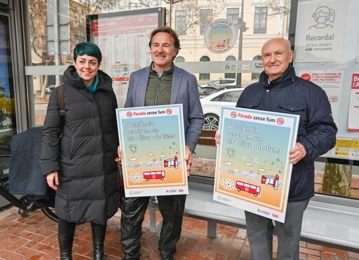 des personnes avec des affiches contre la cigarete dans les arrêts de bus de Valencia 