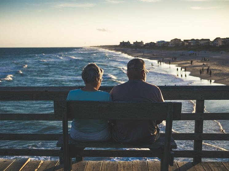 un couple de retraités admirent un coucher de soleil sur la mer