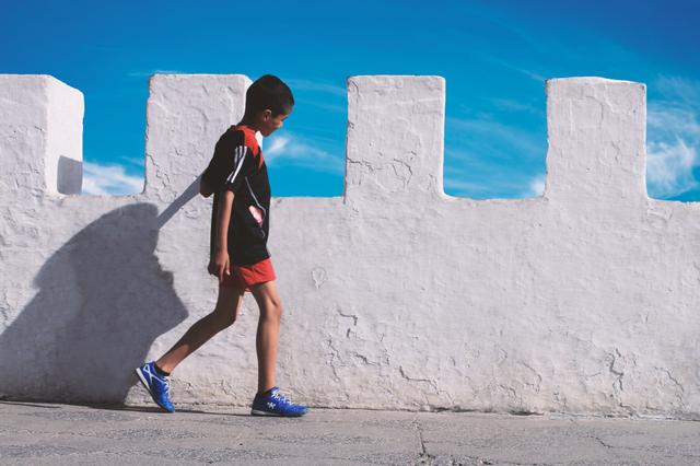 Un enfant marche à Asilah au Maroc sous un ciel bleu 