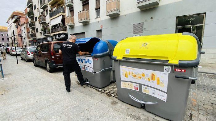 Un homme en train de trier ses déchets dans un conteneur jaune à Valencia