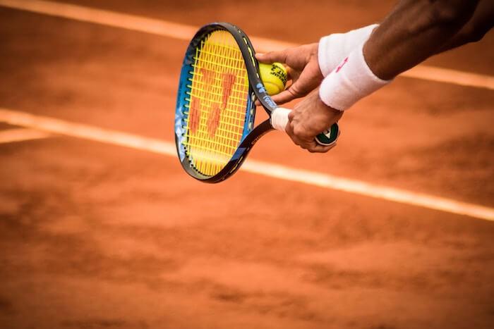 la raquette d'un tennisman en train de servir sur un court de terre battue