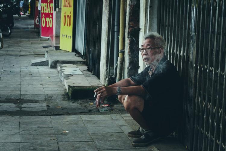 Un vieil homme fume au vietnam, dans la rue