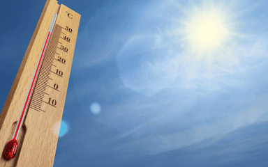 Un thermomètre avec un ciel bleu et un grand soleil derrière