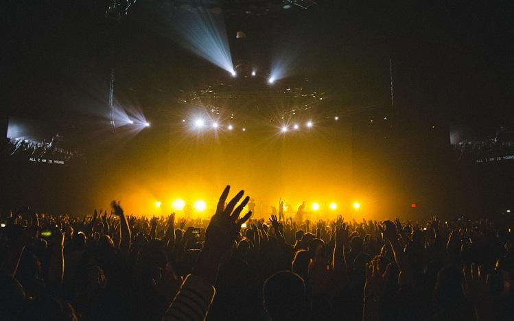 bras levés dans une salle de concert aux lumières tamisées