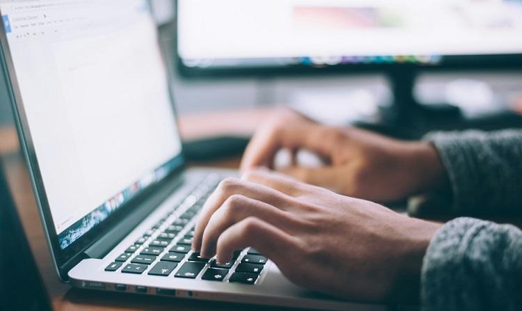 un homme tape sur un clavier d'ordinateur portable