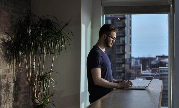 un homme travaille debout avec son ordinateur en télétravail