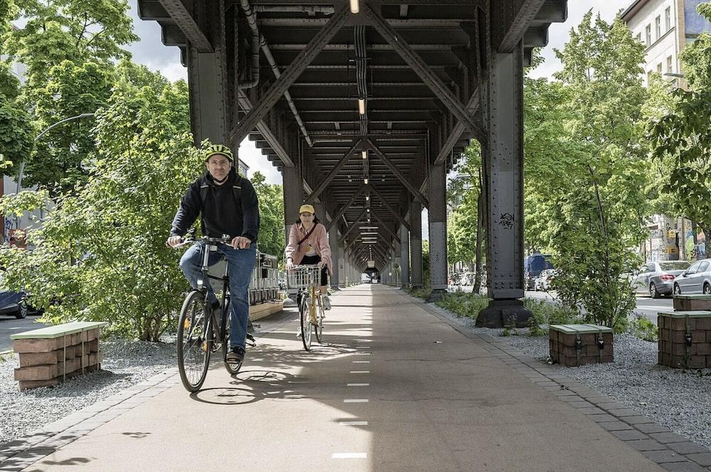 cyclistes sous un viadus ferroviaire entourés de verdure