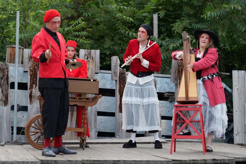 4 personnages sur scène en costume rouges