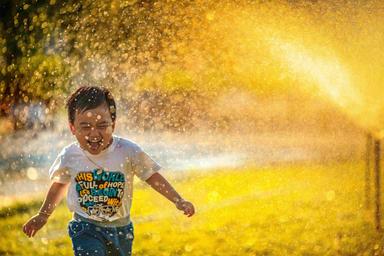 Un enfant sous des jets d'eau. 