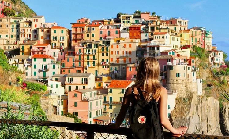 une femme de dos observe des maisons colorées d'un village en Italie