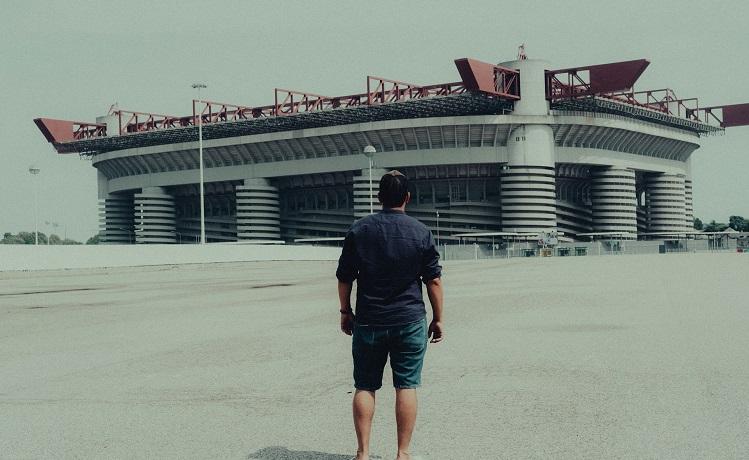 un homme debout devant le stade san siro à milan