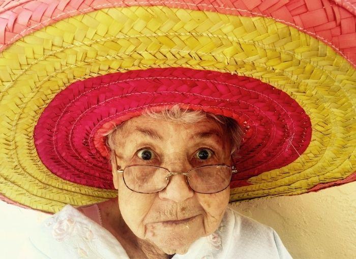 une femme agee avec un chapeau rouge et jaune